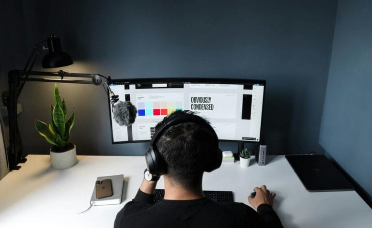 A man using a computer in a stylish home office with a minimalist setup.