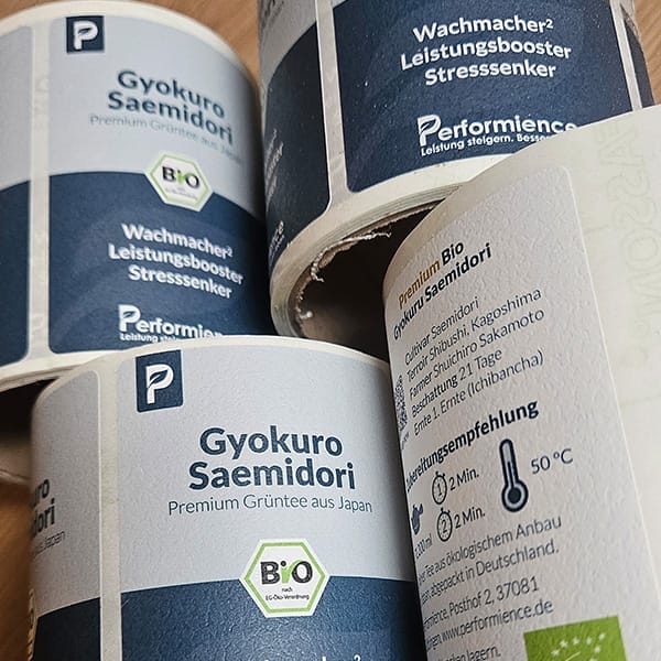 Drei Rollen Etiketten, die durch Grafikdesign entwickelt wurden auf einem Holztisch.